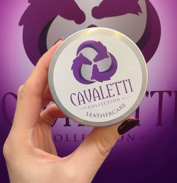 Hand holding a Cavaletti Collection Leathercare tin against a purple branded background.