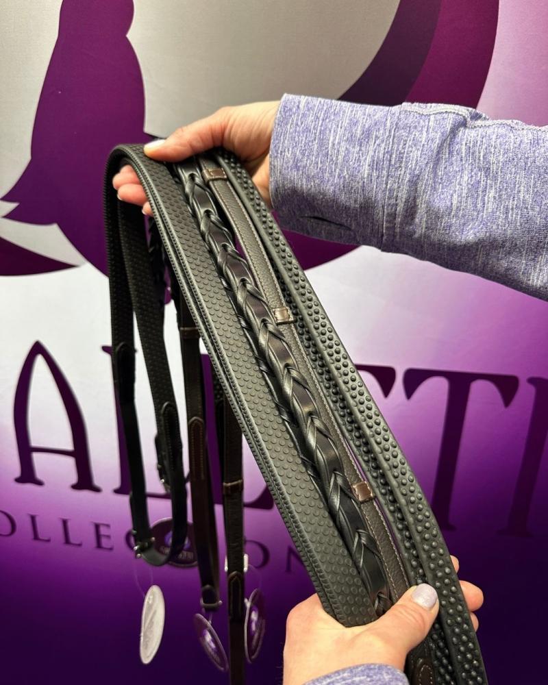 Hands holding a selection of Cavaletti Collection black leather reins, including plaited, rubber grip and laced styles