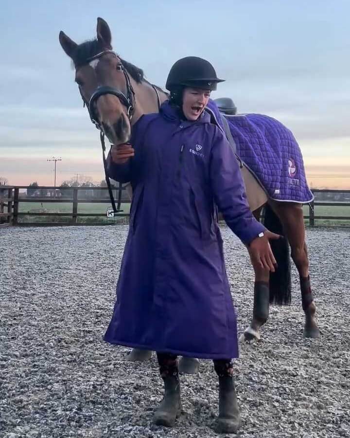 Horse standing in an arena wearing a Cavaletti exercise rug, handled by a rider from Harrys New Chapter during winter training.