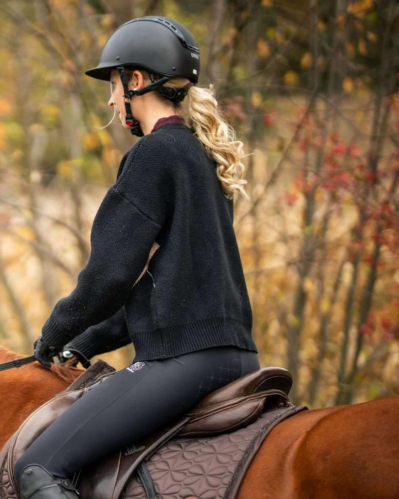 Rider hacking a horse through an autumn landscape wearing a helmet and saddle pad Cavaletti Collection.