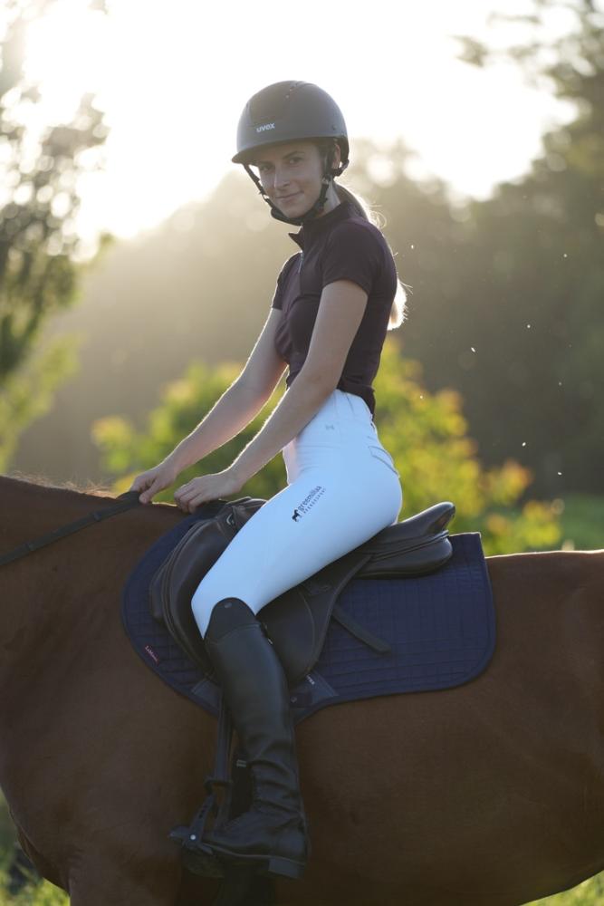 rider-navy-saddle-pad-chestnut-horse-outdoors.jpg Rider smiling on a chestnut horse with a navy saddle pad, outdoors at golden hour